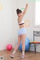 A woman in a sports bra top and blue shorts doing a yoga pose.