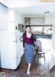 A woman standing in a kitchen next to a refrigerator.