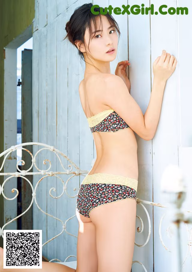 A woman in a bikini leaning against a wall.