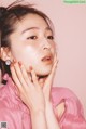 A woman in a pink shirt with her hands on her face.