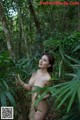 A naked woman standing in the middle of a forest.