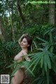 A naked woman standing in the middle of a forest.