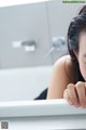 A woman sitting in a bathtub with her hand on the edge of the tub.