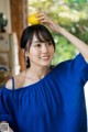 A woman in a blue dress holding a lemon on her head.
