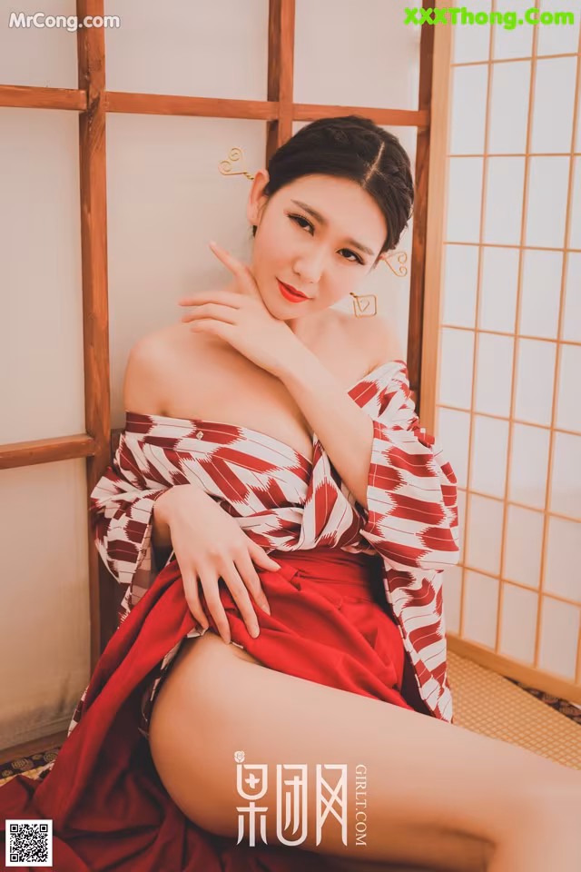 A woman in a red and white kimono sitting on the floor.