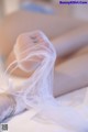 A woman laying on a bed with a veil over her head.