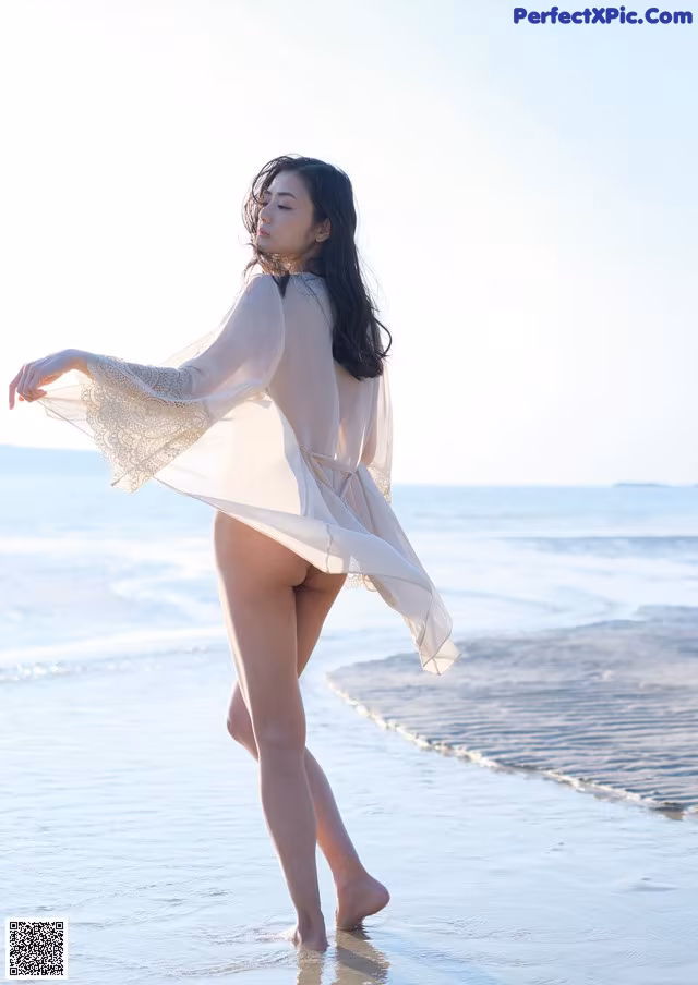 A woman standing on a beach next to the ocean.