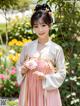 A woman in a pink and white dress holding a flower.