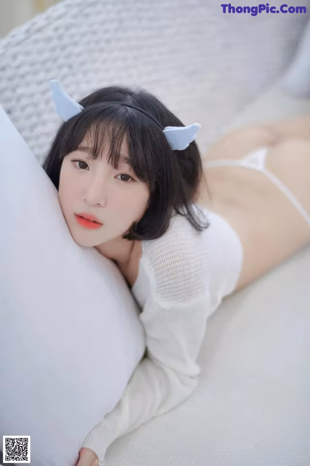 A woman laying on top of a white pillow.