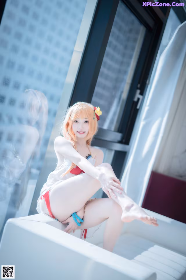 A woman in a red bikini sitting on a white couch.