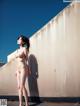 A nude woman standing in front of a wall.