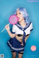 A woman in a sailor outfit holding a lollipop.