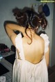 A woman in a white dress standing in a kitchen.