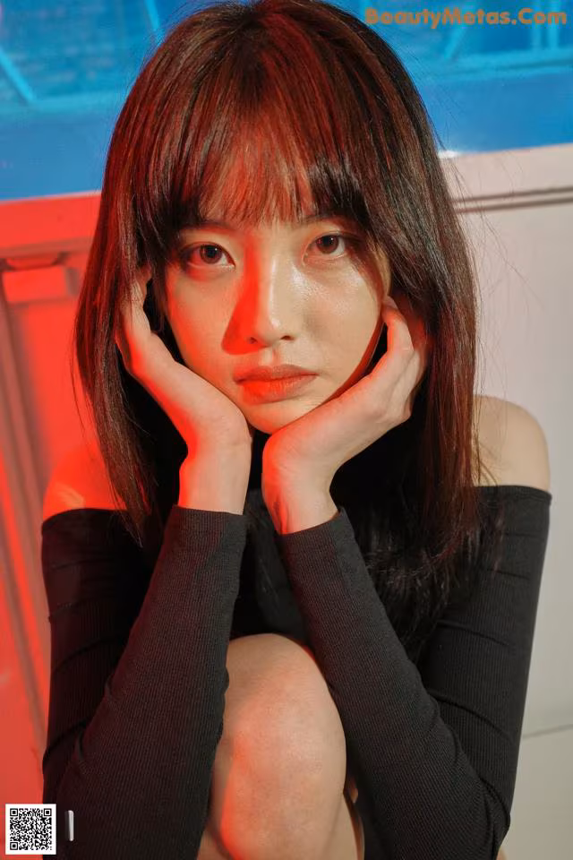 A woman sitting on a chair with her hand on her chin.