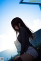 A girl with long black hair sitting on a ledge.