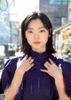 A woman in a purple shirt is posing for a magazine.