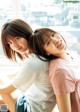 Two young women sitting next to each other on a window sill.